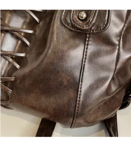 Detailed view of dark brown vintage leather bag with woven side textures and metallic rivets