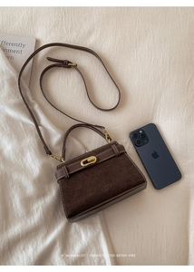 Close-up of retro brown leather bag with gold buckle and white contrast stitching