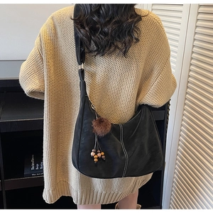 Detail of black crescent hobo bag featuring white contrast stitching and beaded fur charm