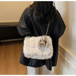 Dettaglio borsa a tracolla in peluche bianca con catena dorata e ciondolo a coniglio