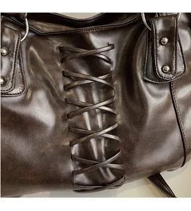 Detailed view of dark brown distressed leather bag with woven cross-tie design