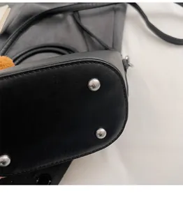 Dettaglio del fondo di una borsa a secchiello in pelle nera con piedini in metallo
