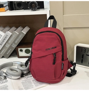 Detail of red plaid chest bag with zipper pocket and brand logo in a retro setting