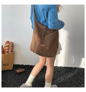 Detail of retro dark brown plush tote bag with logo patch and textured fleece surface