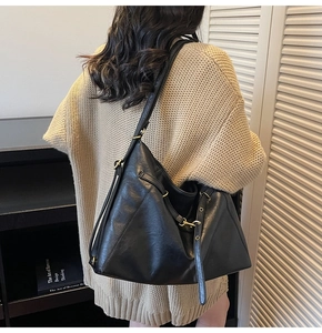 Close-up of black leather tote bag featuring gold zipper and adjustable wide strap