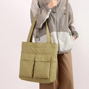 Close-up of olive green nylon tote bag with utility cargo pockets and wide strap