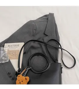 Borsa minimalista in pelle nera opaca con manico circolare e ciondolo orsetto di peluche