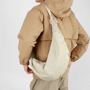 Side view of beige nylon crescent bag featuring drawstring pleats and lightweight design
