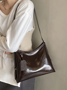 Deep brown glossy pleated leather shoulder bag with adjustable strap in side view