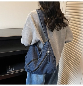 Detail of blue denim crossbody bag featuring textured fabric and functional side pocket