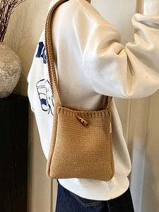 Sac seau en tricot marron avec bouton en bois et texture tissée porté par le mannequin