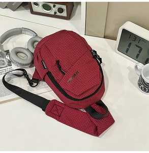 Detail of red checkered crossbody bag with adjustable strap on a minimalist desk