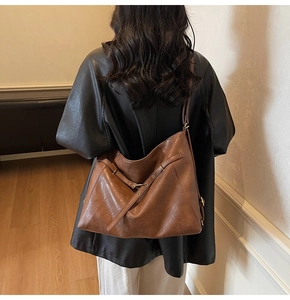 Detail of vintage brown leather crossbody bag featuring wide strap and metal buckle accent