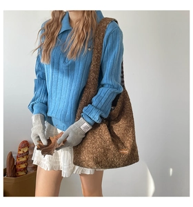 Brown fuzzy tote bag styled with a blue polo sweater and white layered mini skirt