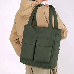 Detail view of dark green quilted tote bag with two front pockets on shoulder