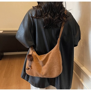 Detail of vintage brown tote bag with contrast stitching and plush pom-pom pendant
