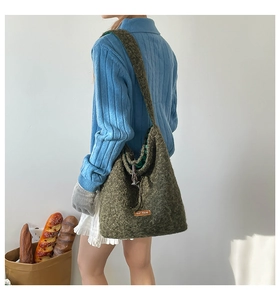 Detail of dark green plush tote bag with brown leather patch and plaid lining