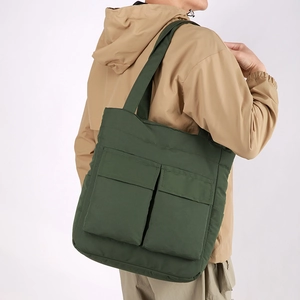 Detail of dark green large tote bag with big front flap pockets on a model