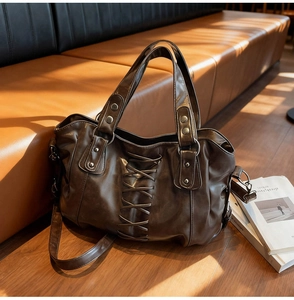 Close-up of a vintage dark brown tote bag with crisscross straps and metal rivets