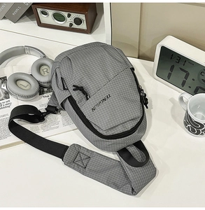 Close-up of gray checkered sling bag with front zipper pocket and adjustable strap