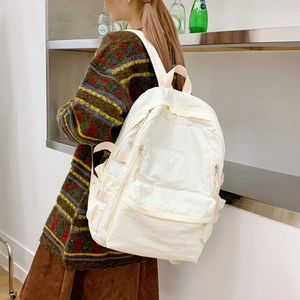 Seitenansicht des weißen Nylon-Rucksacks mit Doherty-Schriftzug und verstellbaren Schnallen
