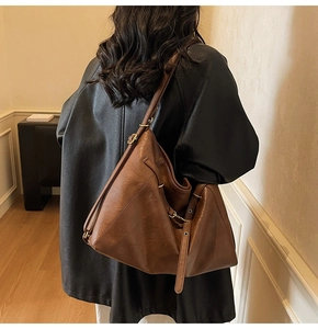 Detail of vintage brown hobo bag showing soft leather texture and gold buckle accents