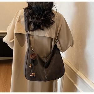 Detail of dark brown suede crescent bag with white contrast stitching and tassel