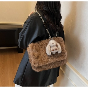 Dettaglio borsa di peluche marrone con ciondolo a coniglio su giacca di pelle