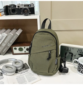 Close-up of olive green checkered chest bag with brand label and durable zippers