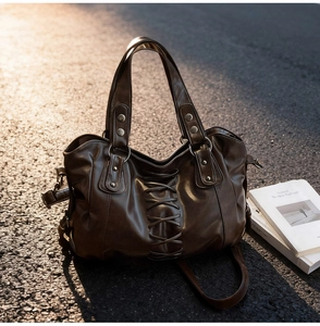 Close-up of vintage brown leather tote bag with lace-up detail and retro studs