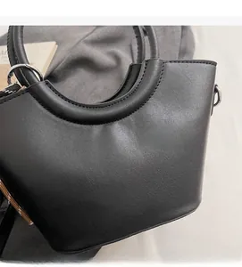 Dettaglio della borsa nera in pelle sintetica che mostra la trama liscia e il design curvo