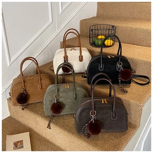 Detailed display of vintage pillow bags in five colors with plush ball charms on stairs