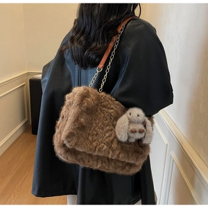 Dettaglio borsa tote in peluche marrone con ciondolo a coniglio grigio e catena d'oro