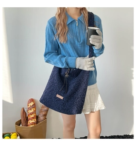 Detail of dark blue fleece tote bag with brand label and drawstring on a model