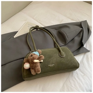 Close-up of green suede shoulder bag with MIQIER branding and cute bear charm detail