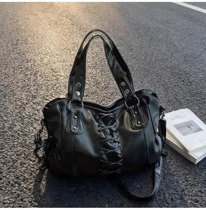 Close-up of black punk tote bag with cross-lace detailing and silver metal rivets