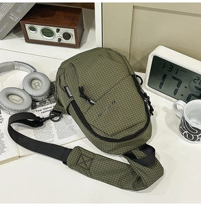 Macro view of green checkered crossbody bag with adjustable strap and brand logo