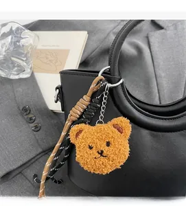 Dettaglio di un ciondolo a forma di orsetto di peluche con cordino su borsa in pelle nera