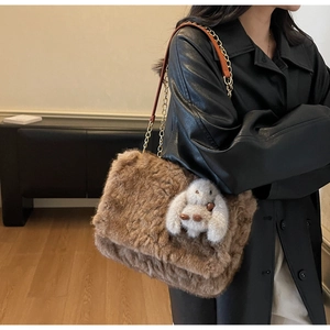 Dettaglio borsa a tracolla in peluche marrone con catena dorata e ciondolo a coniglio