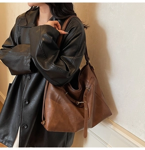 Detail view of a large brown Maillard tote bag with adjustable straps on a model