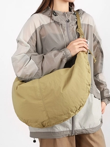 Large mustard yellow nylon crescent crossbody bag shown on model in a casual style