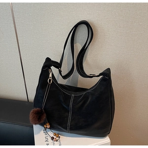Detail of black Hobo bag with white contrast stitching and ethnic bead charm