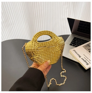 Dettaglio della trama in metallo dorato intrecciato e della catena sottile di questa borsa