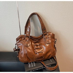 Detail of vintage brown tote bag featuring lace-up leather weave and silver metal rivets