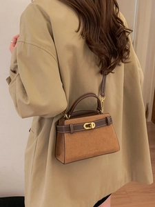 Retro trapezoidal crossbody bag in brown frosted leather shown on a trench coat model