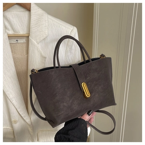 Detail of caramel faux leather handbag with golden capsule buckle and twin handles