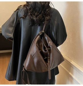 Detail of soft dark brown leather shoulder bag with adjustable strap and gold hardware