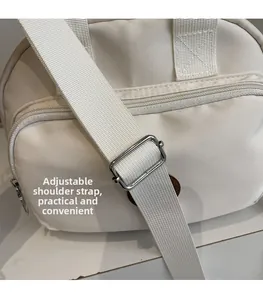 Detail view of white canvas crossbody bag featuring adjustable shoulder strap and silver buckle