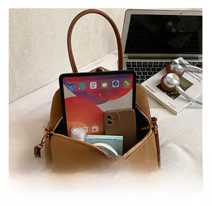 Macro view of retro brown shoulder bag showing spacious interior with tablet and phone