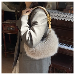 Détail du sac croissant en fausse fourrure beige avec perles et poignée en bois